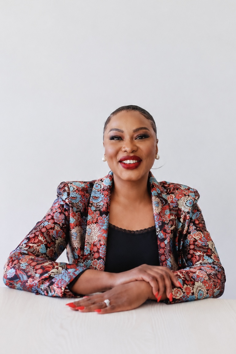 Pastor Valerie smiling while seated at a table in a floral blazer